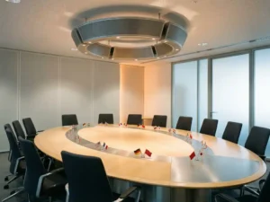 Moderne vergaderzaal met ovale tafel, nationale vlagpinnen als taalmarkeringen en professioneel plafondluidsprekersysteem.