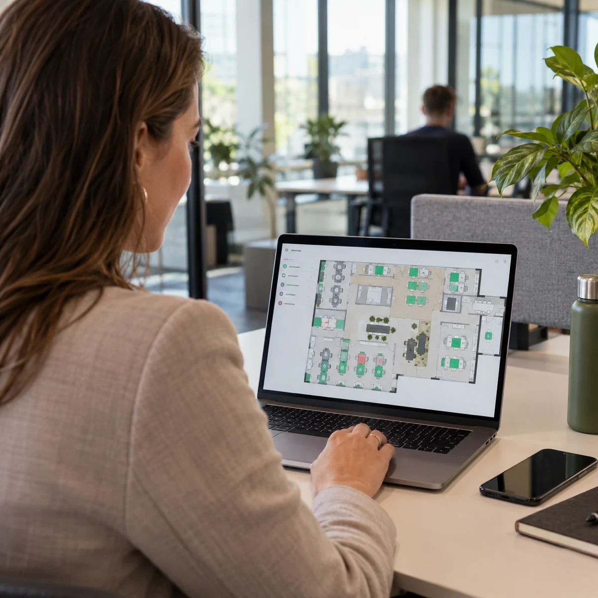 Medewerker bekijkt een digitale kantoorplattegrond met beschikbare werkplekken.